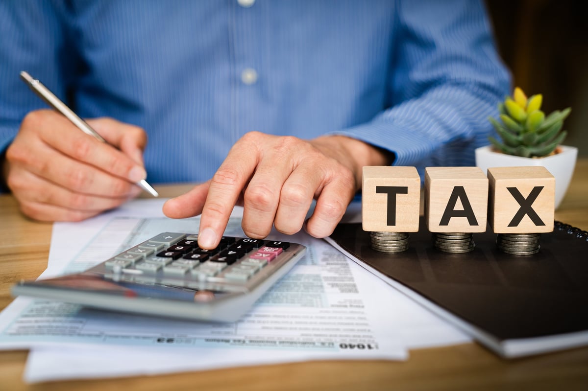 Business professional calculating tax with calculator and financial documents